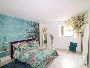 A bedroom with a bed, a dresser, a mirror, and a window with a view.