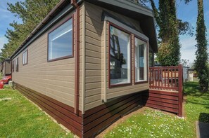 Ein Bungalow mit einer Veranda, großen Fenstern und einer sichtbaren Garagentür.