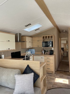 Eine kleine Küchenzeile in einem Wohnmobil mit Mikrowelle, Kaffeemaschine und einer kleinen Essecke.