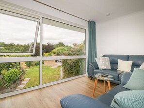 A modern living room with a large window, a blue sofa, and a small coffee table.