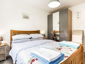 A bedroom with a wooden bed, a wardrobe, a nightstand, and a bedside table.