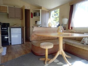 A compact living space with a kitchenette, a dining table, and a sofa. - Swale Dale 5, Long Preston (Skipton)