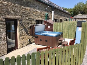 A stone building with a hot tub, wooden deck, and a wooden fence. - Oak Cottage, Newcastle Emlyn (Llandysul)