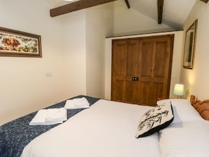 Ein Hotelzimmer mit Bett, Holzschrank, gerahmtem Bild an der Wand und Lampe.