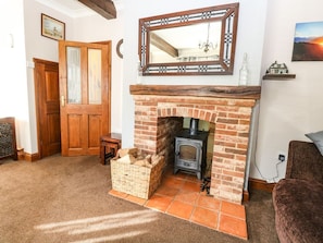 A room with a fireplace, wooden doors, a mirror, and a small table. - Rose cottage, Cromer (Cromer)
