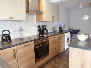 A modern kitchen with wooden cabinets, a built-in oven, a microwave, and a coffee maker.