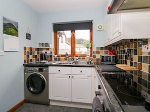 A compact kitchen with a washing machine, a sink, and a stove. - The Laurels, Backbarrow (Ulverston)
