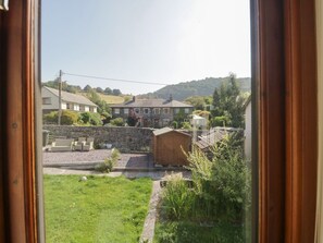A view of a residential area with a stone wall, a wooden shed, and a grassy yard. - The Laurels, Backbarrow (Ulverston)