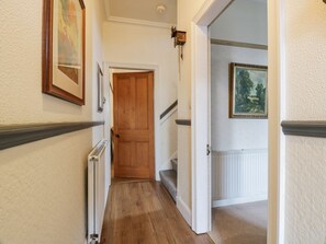 A hallway with a wooden door, a radiator, and a framed picture on the wall. - Hildawn, based within Dumfries (Dumfries)