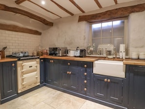 A kitchen with a white stove, a coffee machine, and a window with blinds.