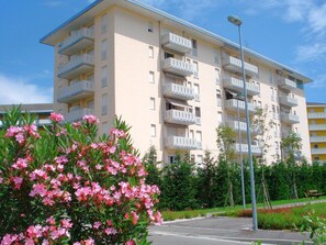 A multi-story residential building with balconies, a parking lot, and surrounding greenery. - Apartment in Porto Santa Margherita (Caorle)