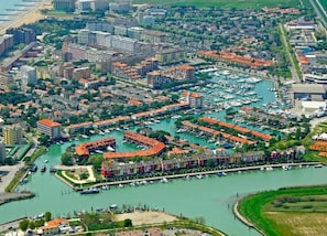 An aerial view of a marina with boats docked, surrounded by residential buildings and a bridge. - Apartment in Porto Santa Margherita (Caorle)