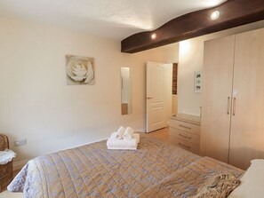Ein Schlafzimmer mit Bett, Kommode, Spiegel und einer Tür zu einem weiteren Raum.