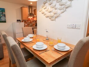 A dining area with a wooden table set for four, white plates, bowls, and glasses of orange juice.