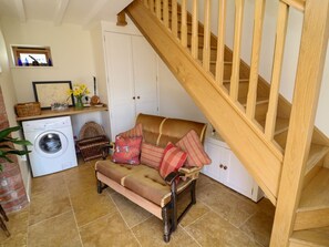 Ein gemütlicher Wohnbereich mit einer Couch, einer Waschmaschine, einer Holztreppe und einer weißen Tür.