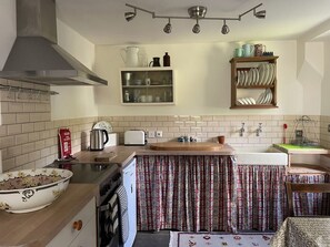 A kitchen with a stove, oven, sink, and a cabinet above the counter. - The Shed, Tiddington (Stratford-upon-Avon)
