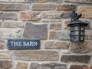 Eine Steinsäule mit einem Schiefer Schild, auf dem 'THE BARN' steht, und einer schwarzen Laterne im Laternenstil.