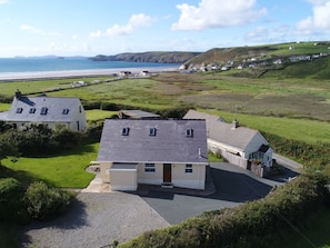 Ein Küstenanwesen mit einem Haus, einer Auffahrt und Blick auf Strand und Klippen.