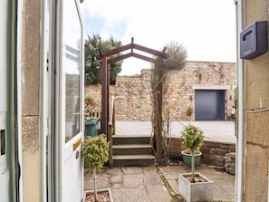 A stone building with a garage door, a wooden pergola, and potted plants. - Riverside, Grassington (Grassington)
