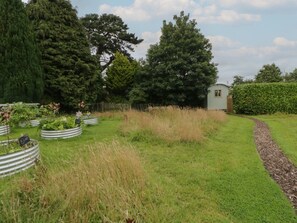 A garden with metal planters, a small shed, and a hedge. - Flora's Hut, Liskeard (Liskeard)