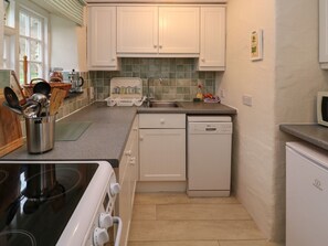 A compact kitchen with white cabinets, a dishwasher, a microwave, and a stove.