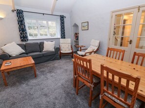 A cozy living room with a sofa, wooden chairs, a small table, and a dining table.