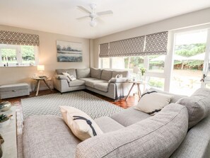 A living room with a grey sofa, a coffee table, a side table with a lamp, and a painting on the wall. - Church Farm Bungalow, Weybourne (Holt)