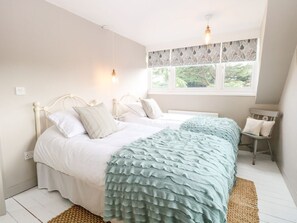 A bedroom with two beds, a window with lace curtains, and a small chair. - Church Farm Bungalow, Weybourne (Holt)