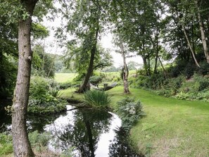 A serene garden with a pond, trees, and a picnic table.