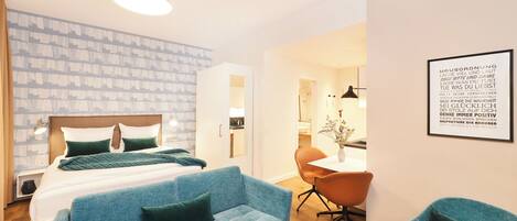Een moderne hotelkamer met een bed, een blauwe bank, een bureau en een citaat in een lijst op de muur.