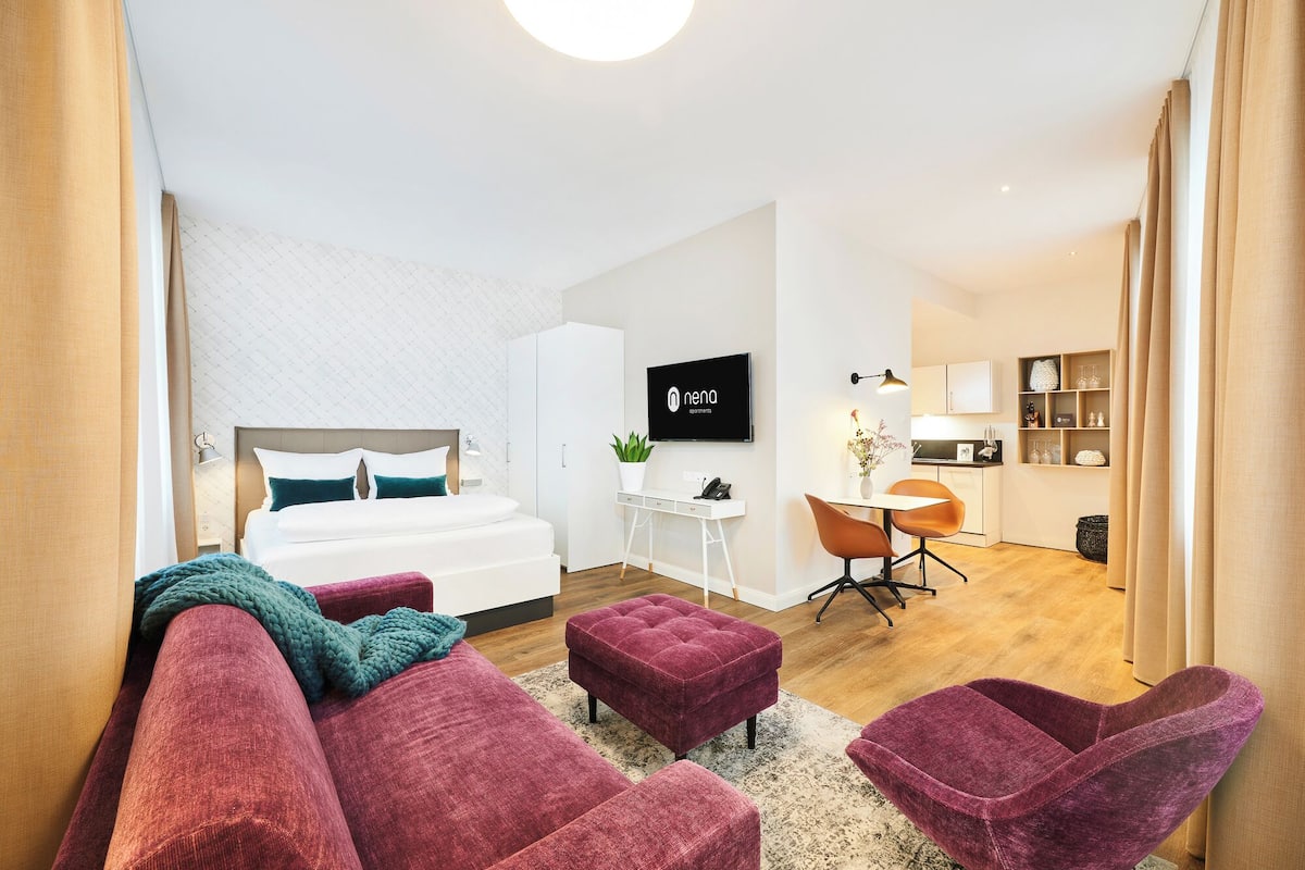 Habitació d'hotel moderna amb un llit gran, escriptori, televisió i zona de seients amb un sofà i cadires.