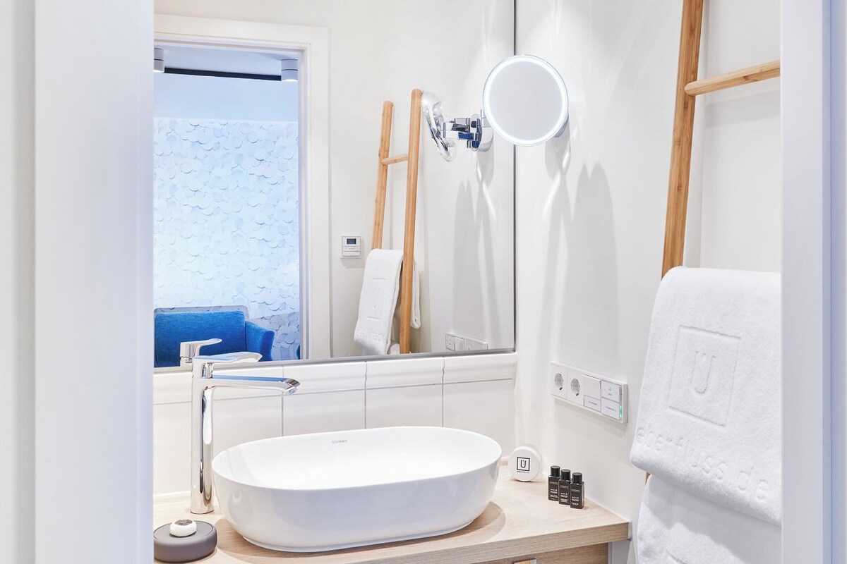 Une salle de bain moderne avec un grand lavabo ovale, un miroir et un meuble-lavabo en bois.