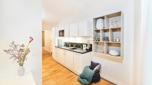Een moderne keuken met witte kasten, een houten aanrecht en een inbouwkastje met decoratieve spullen.