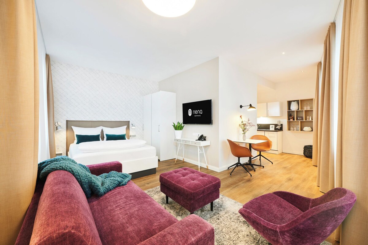Une chambre d’hôtel moderne dotée d’un grand lit, d’un bureau, d’une télévision et d’un coin salon avec un canapé et des fauteuils.