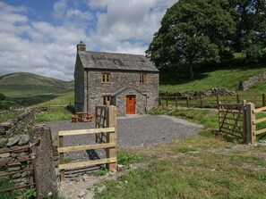 Ein Steinhaus mit einer Holztür, einem Holztor und einer Steinmauer.