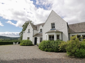 A white building with a gravel driveway and a small seating area. - Fordie Lodge, Comrie (Crieff)