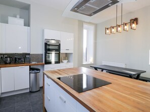 Una cucina moderna con un piano di lavoro in legno, forno integrato e zona pranzo con tavolo.