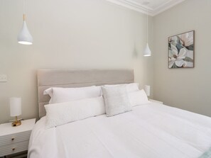 Una camera da letto con un letto, comodini e una lampada a parete.