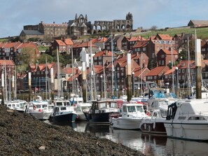 A marina with boats docked, a historic building in the background, and red-roofed houses. - Waddleduck Retreat in Whitby (Whitby)