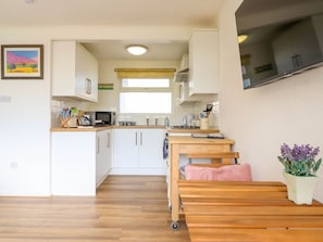 Una cocina compacta con armarios blancos, un microondas y una ventana sobre el fregadero.