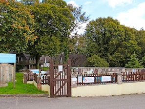 A gated swimming pool area with a wooden fence, a signboard, and a small building. - Manorcombe 40, near Drakewalls (Callington)