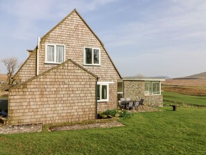 A two-story house with a stone extension, a small garden, and a view of the countryside. - Netherscar, Ingleton (Carnforth)