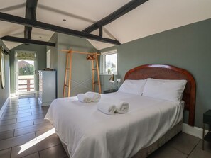 A bedroom with a bed, a ladder, a desk, and a window.
