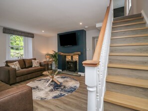 Ein Wohnzimmer mit einer Couch, einem Couchtisch, einem Kamin und einem an der Wand befestigten Fernseher.
