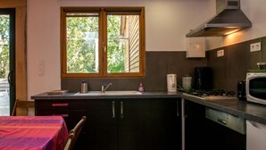 A compact kitchen with a window, a microwave, a coffee maker, and a sink. - Chalet Jardin Les Fées (Saint-Remèze)