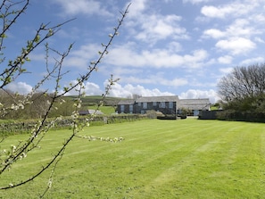 A large building with multiple windows, surrounded by a well-maintained lawn and stone walls.