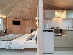 A cozy cabin with a bed, a kitchenette, and a TV mounted on the wall.