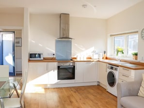 A compact kitchen with a microwave, oven, and washing machine, wooden countertops, and a window with a view. - View Apartment, Inverness (Inverness)