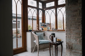 A corner room with a wicker chair, a table with a coffee pot, and a 'hello' sign.