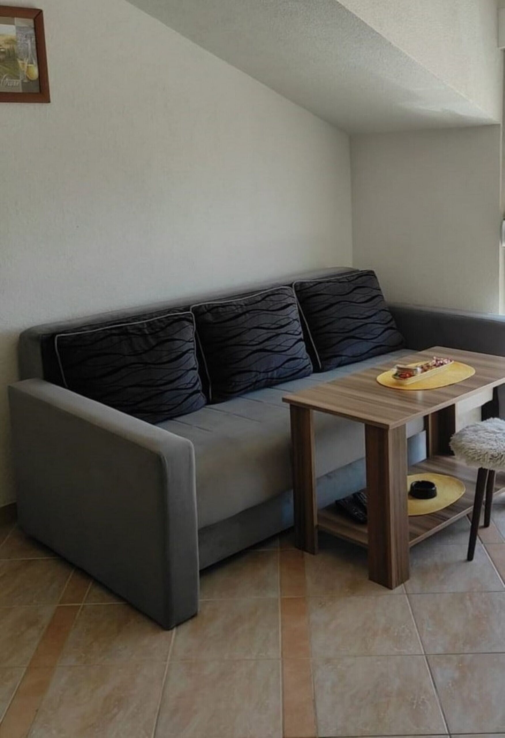 A modern living room with a grey sofa, a wooden coffee table, and a small round table with a yellow base.